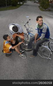 High angle view of a teenage boy and a boy gesturing at their friend sitting on a low rider bicycle