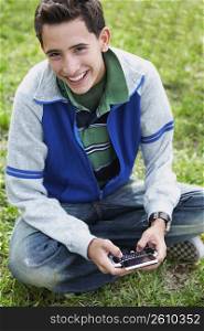 High angle view of a teenage boy smiling and using a mobile phone