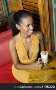 High angle view of a teenage girl sitting at the table with a mug of cappuccino