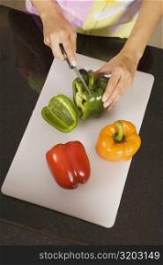 High angle view of a woman cutting a green bell pepper on a cutting board