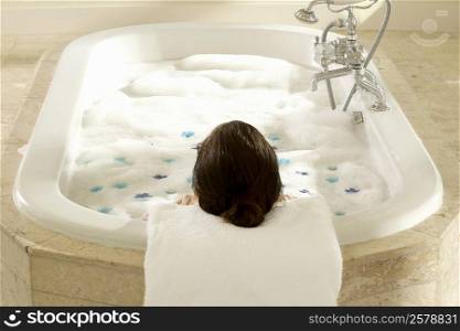 High angle view of a woman in a bubble bath with flower petals