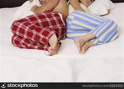 High angle view of a young couple lying back to back on the bed