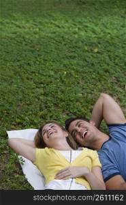 High angle view of a young couple lying in a park and laughing