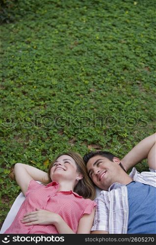 High angle view of a young couple lying in a park and smiling