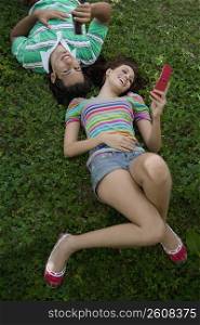 High angle view of a young couple lying in a park and using mobile phones