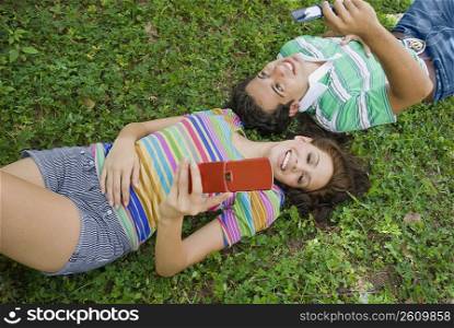 High angle view of a young couple lying in park and holding a mobile phone
