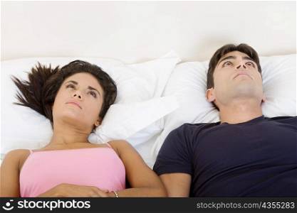 High angle view of a young couple lying on the bed and looking up