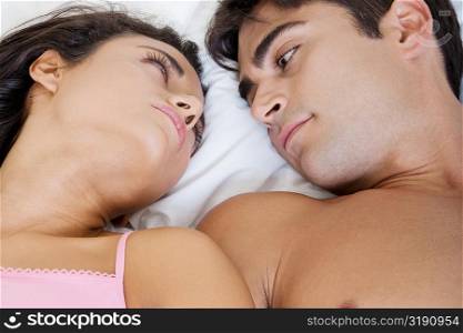 High angle view of a young couple lying on the bed looking at each other