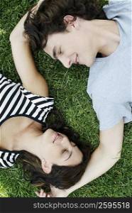 High angle view of a young couple lying on the grass in a park