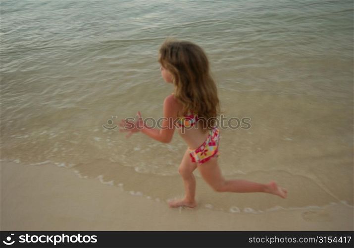High angle view of a young girl (6-8) running in water, Moorea, Tahiti, French Polynesia, South Pacific
