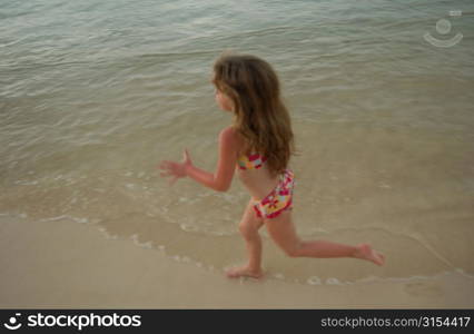 High angle view of a young girl (6-8) running in water, Moorea, Tahiti, French Polynesia, South Pacific