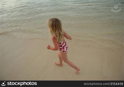 High angle view of a young girl (6-8) running in water, Moorea, Tahiti, French Polynesia, South Pacific