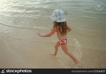 High angle view of a young girl (6-8) wearing a bikini running in water, Moorea, Tahiti, French Polynesia, South Pacific