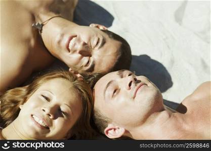 High angle view of a young man and a mid adult man with a young woman lying on the beach