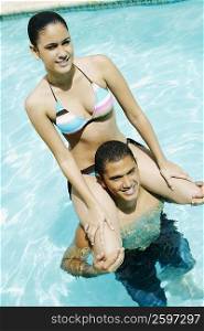 High angle view of a young man carrying a young woman on his shoulders in a swimming pool