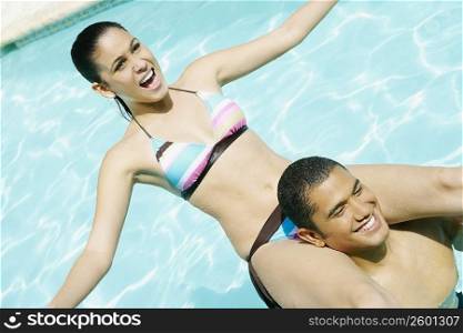 High angle view of a young man carrying a young woman on his shoulders in a swimming pool