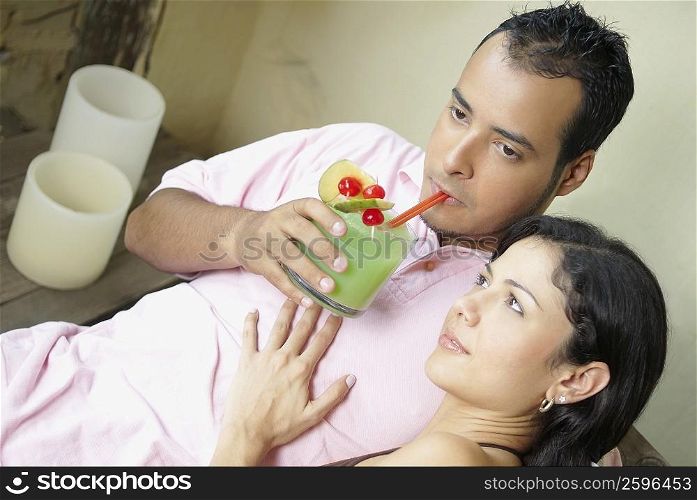 High angle view of a young man drinking juice with a young woman sitting beside him