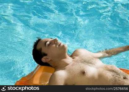 High angle view of a young man lying on a raft in a swimming pool