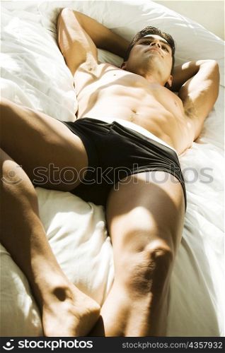 High angle view of a young man lying on his back thinking