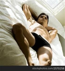 High angle view of a young man lying on the bed thinking