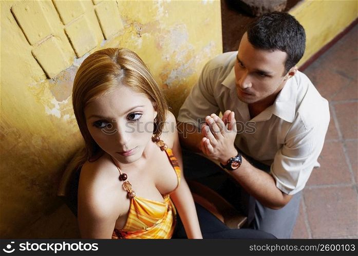 High angle view of a young man pleading in front of a young woman
