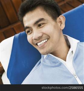 High angle view of a young man reclining on a lounge chair and smiling