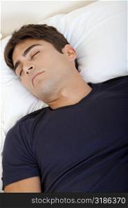 High angle view of a young man sleeping on a bed