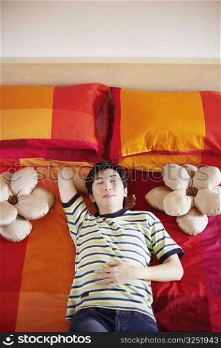 High angle view of a young man sleeping with his hand behind his head