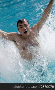 High angle view of a young man splashing water in a swimming pool