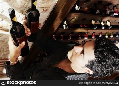 High angle view of a young man taking a bottle from a wine rack