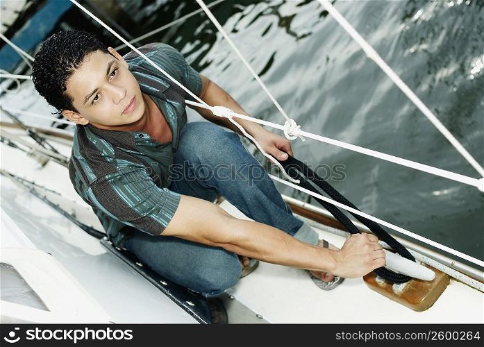 High angle view of a young man tying a rope on a boat