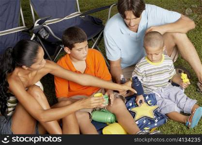 High angle view of a young woman and a mid adult man sitting on the grass with their two children