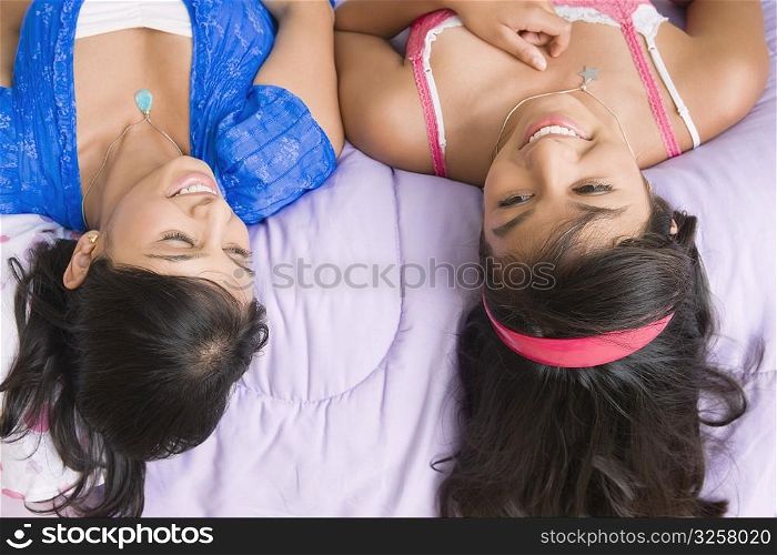 High angle view of a young woman and a teenage girl lying on the bed and smiling