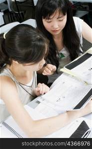 High angle view of a young woman and a teenage girl reading notes in the classroom