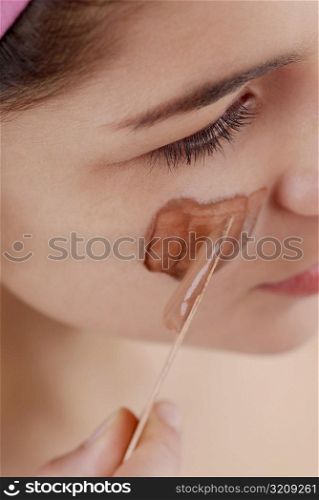 High angle view of a young woman applying a facial mask on her face