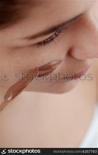 High angle view of a young woman applying a facial mask on her face