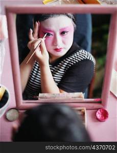 High angle view of a young woman applying eyeliner