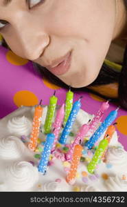 High angle view of a young woman blowing candles on a birthday cake