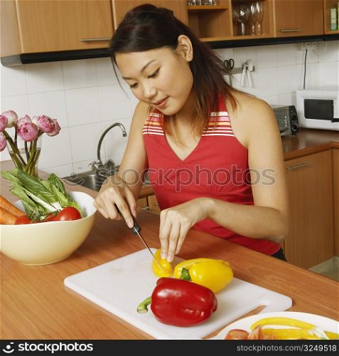 High angle view of a young woman cutting vegetables at the kitchen