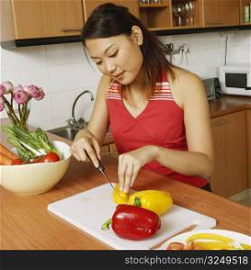 High angle view of a young woman cutting vegetables at the kitchen