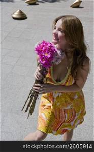 High angle view of a young woman holding a bouquet of flowers and looking away