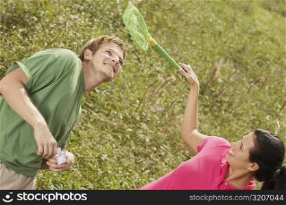 High angle view of a young woman holding a butterfly net over a young man&acute;s head