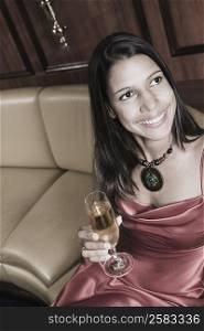 High angle view of a young woman holding a champagne flute and smiling