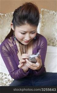 High angle view of a young woman holding a mobile phone smiling