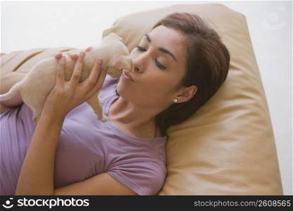 High angle view of a young woman kissing a puppy