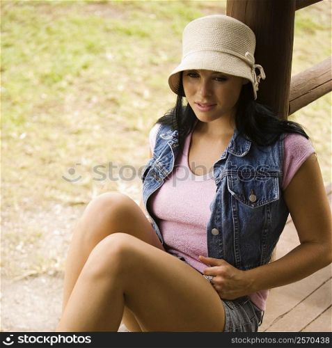 High angle view of a young woman leaning against a wooden post