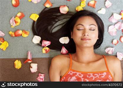 High angle view of a young woman lying down with petals around her