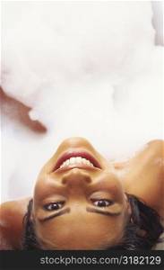 High angle view of a young woman lying in a bubble bath