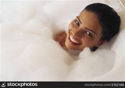 High angle view of a young woman lying in a bubble bath