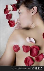 High angle view of a young woman lying on a massage table with rose petals on her back